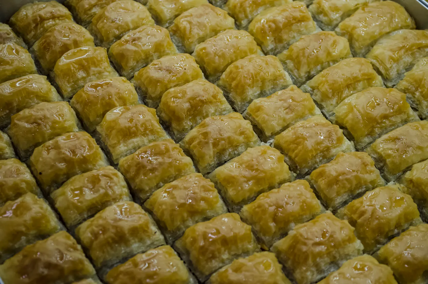 tight rows of syrup-glazed pistachio baklava filling a steel tray