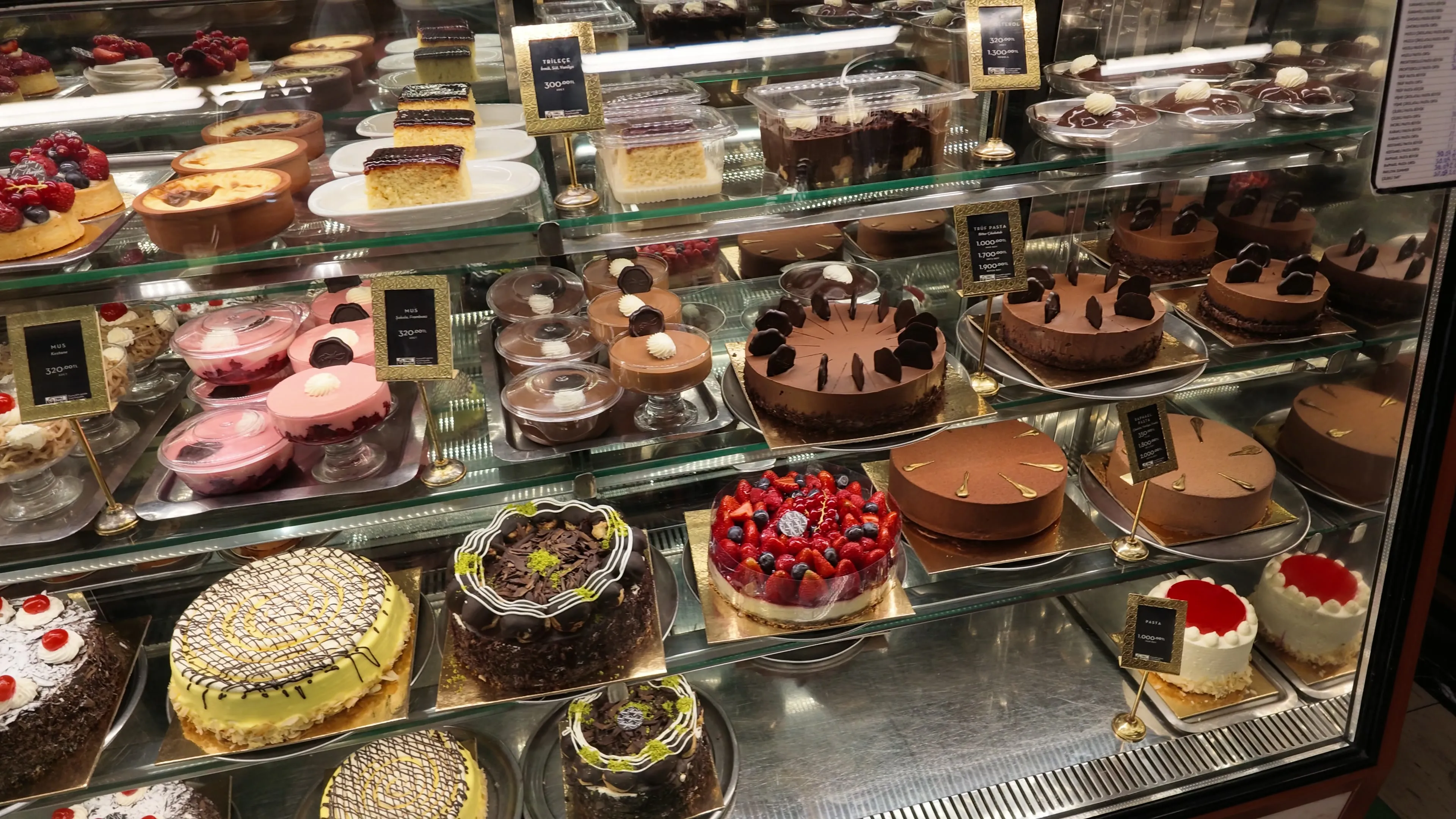 Whole cakes, fruit tarts, and cream desserts fill the glass display at Baylan