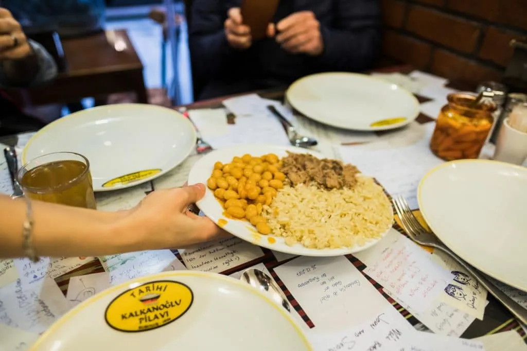 Plate of beans, meat and rice being served to table of foodie guests, taksim evening food tour