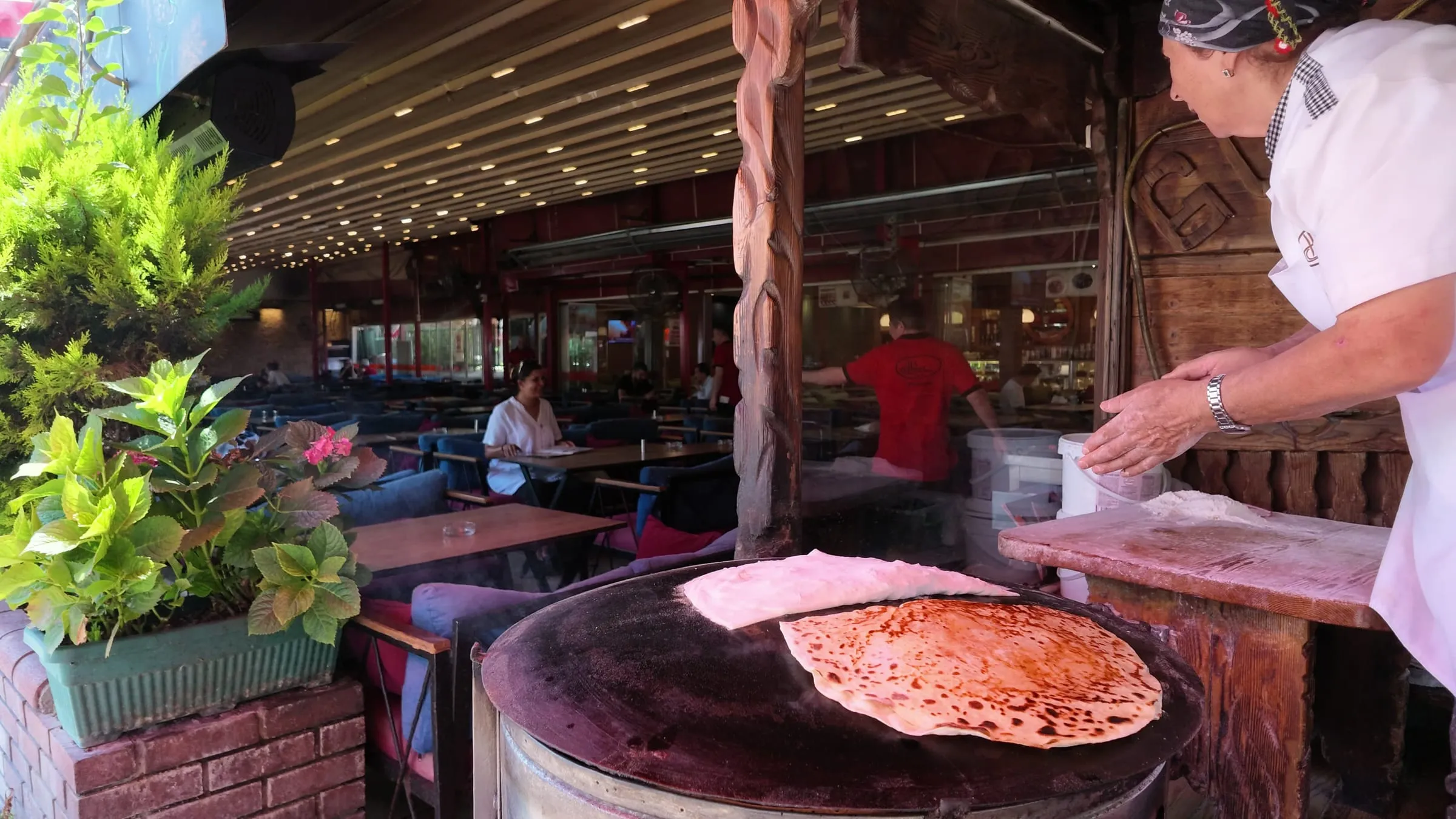 Cook folding filled gözleme as it browns on a wide sac griddle in Beşiktaş