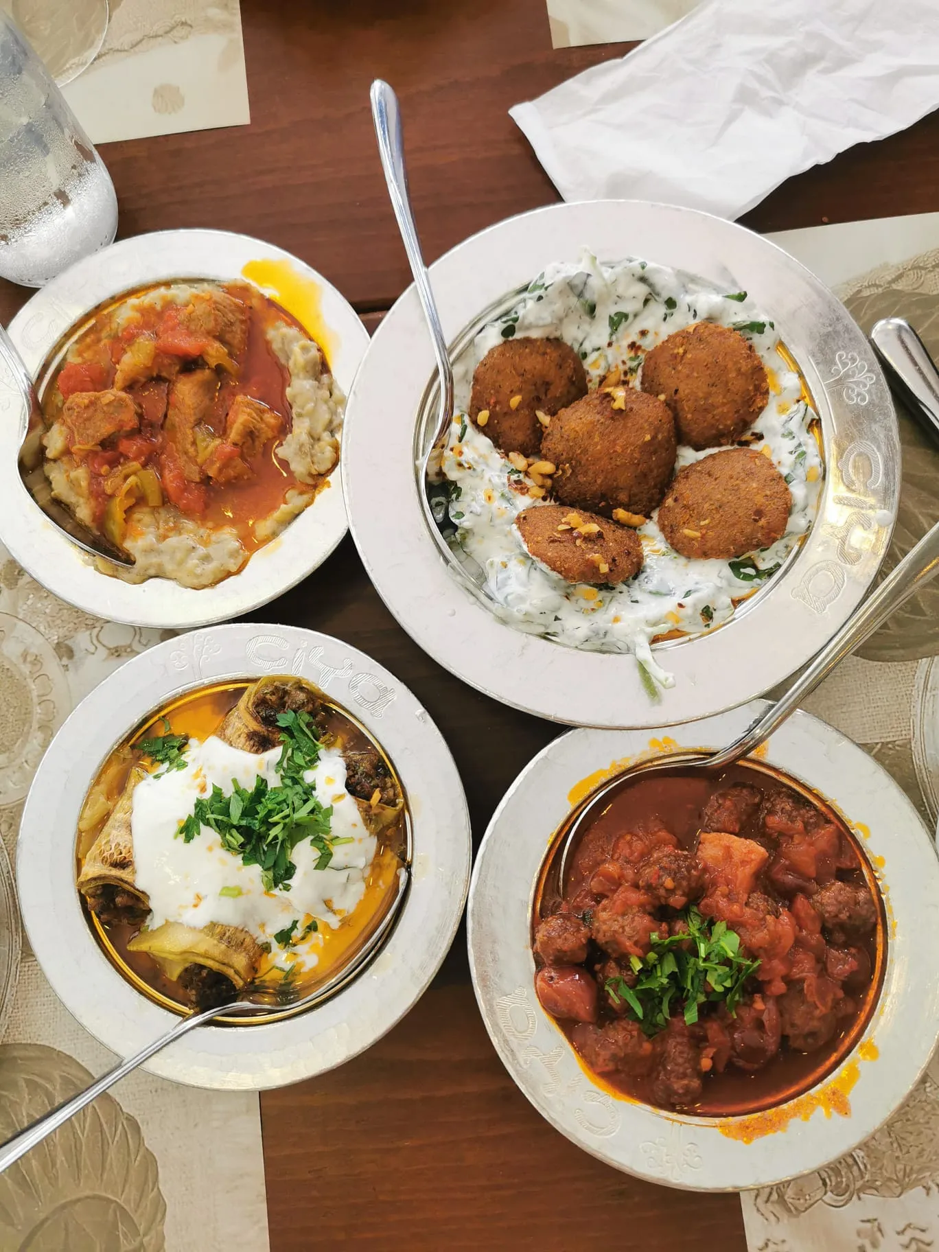 Three bowls and a plate of cooked dishes arranged together on a restaurant table