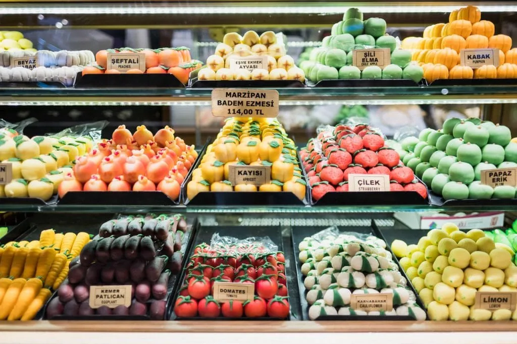 Variety of cute brightly colored marzipan fruit sculptures on display in cabinet during Istanbul culinary tour