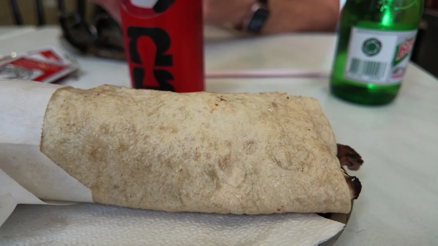 doner durum wrapped in lavash and paper, served with ayran at a counter