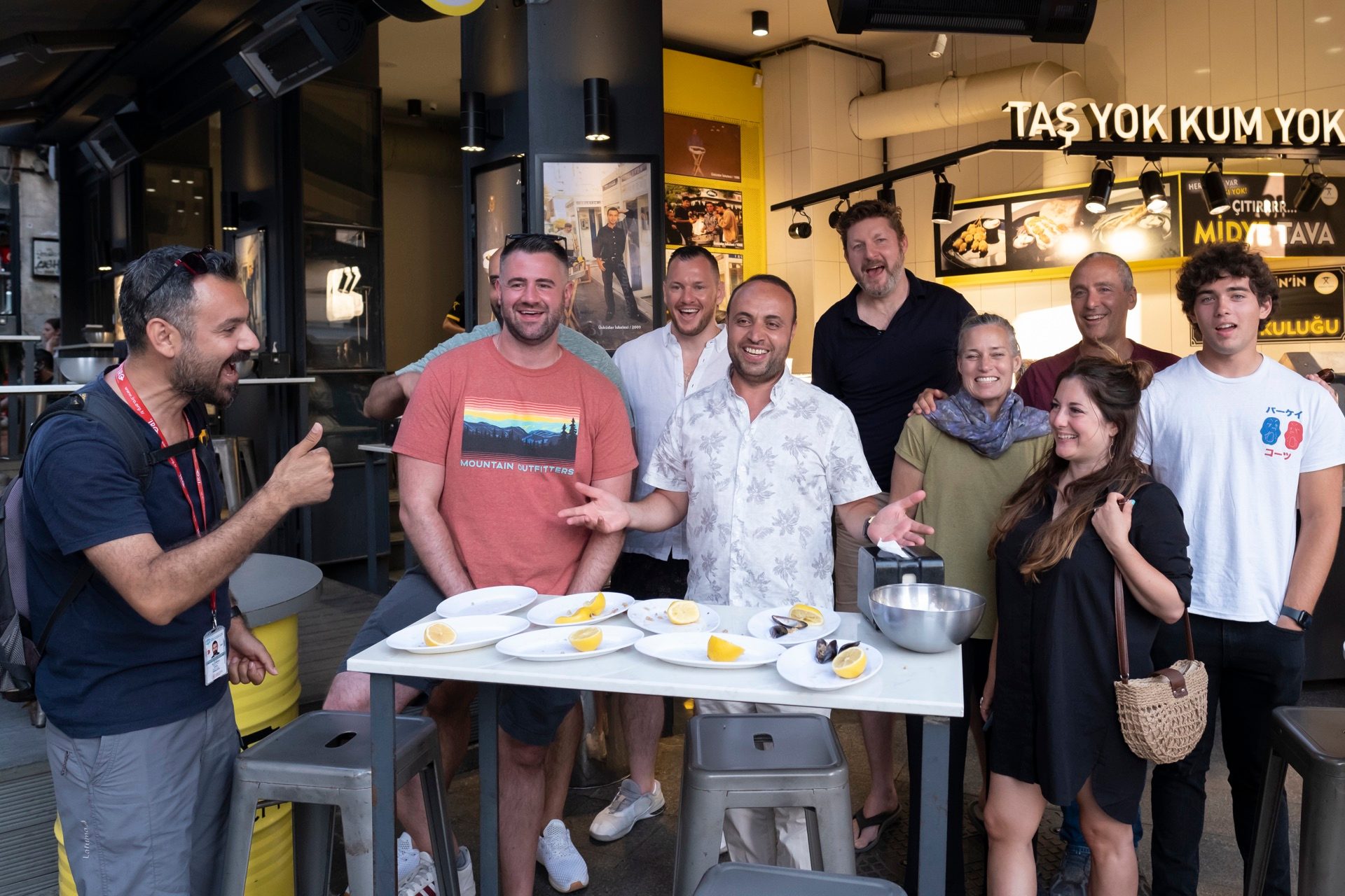 A food tour group smiling with their guide outside a Kadıköy mussel spot in Istanbul