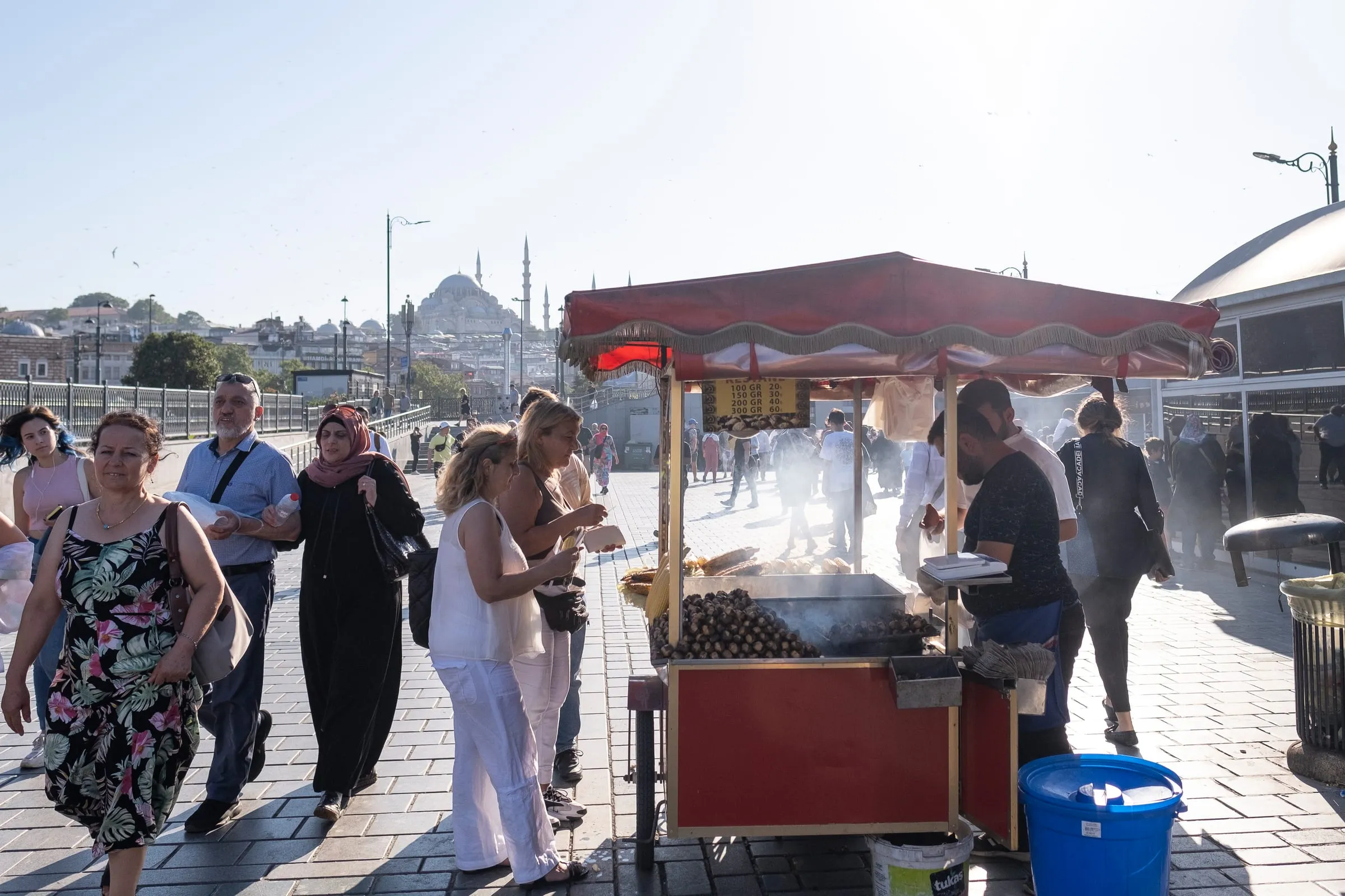 Roasted chestnut and corn cart on Galata Bridge with the old city mosque skyline behind