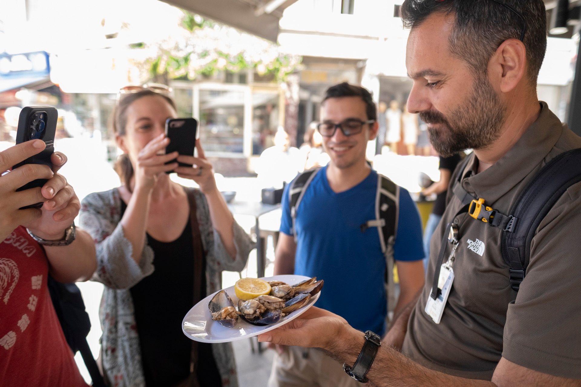 Guide holding a plate of stuffed mussels for waiting guests at an Istanbul midyeci