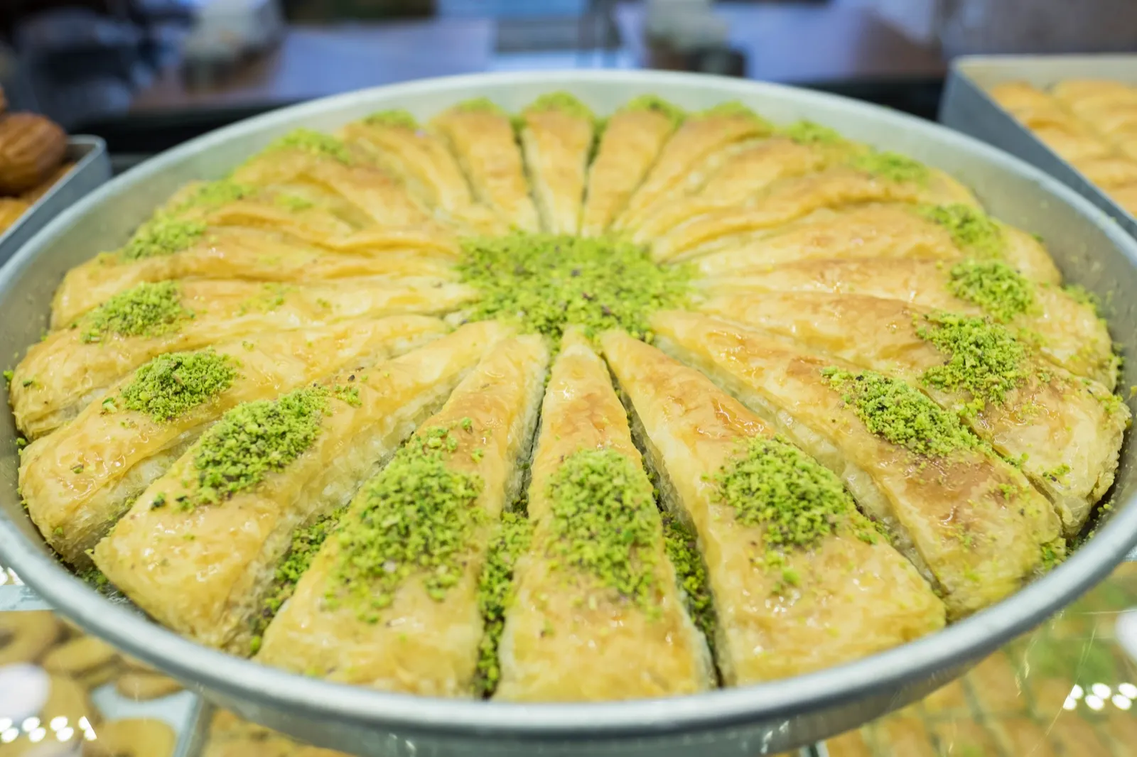 full round tray of syrup-glazed pistachio baklava wedges at an Istanbul bakery counter