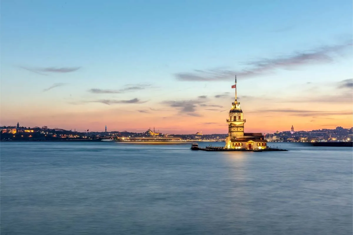 The lit Maiden's Tower on its island in the Bosphorus at dusk, Istanbul skyline behind