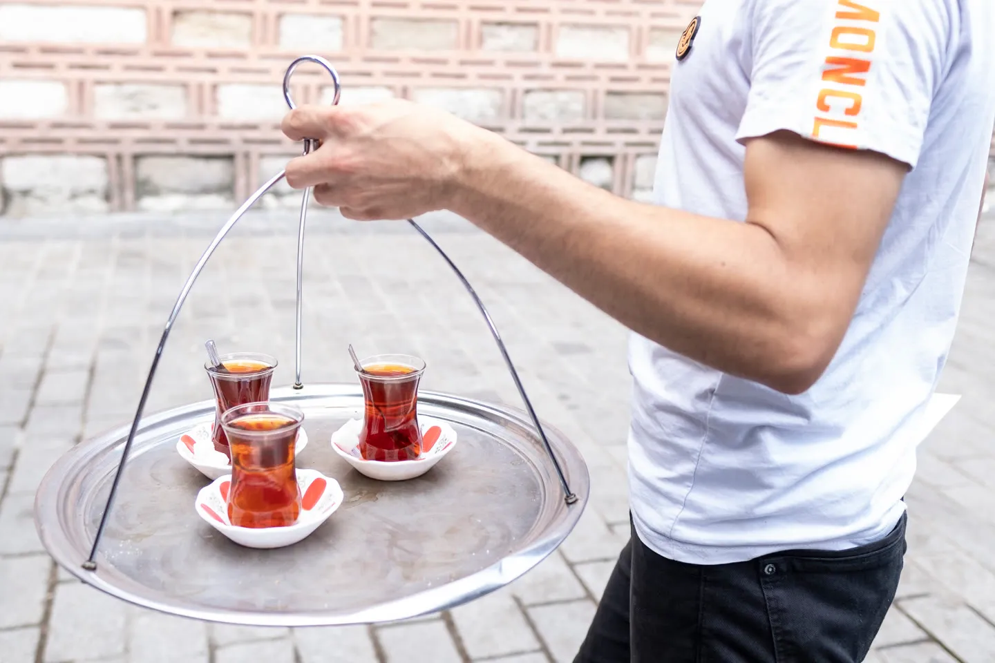 A çay seller carries a swinging tray of Turkish tea glasses through an Istanbul street