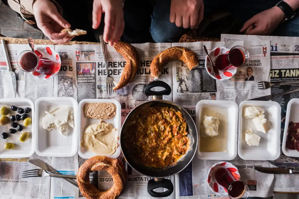 Taste of Two Continents food tour market breakfast of olives cheese eggs cream honey simit Turkish tea laid on newspaper