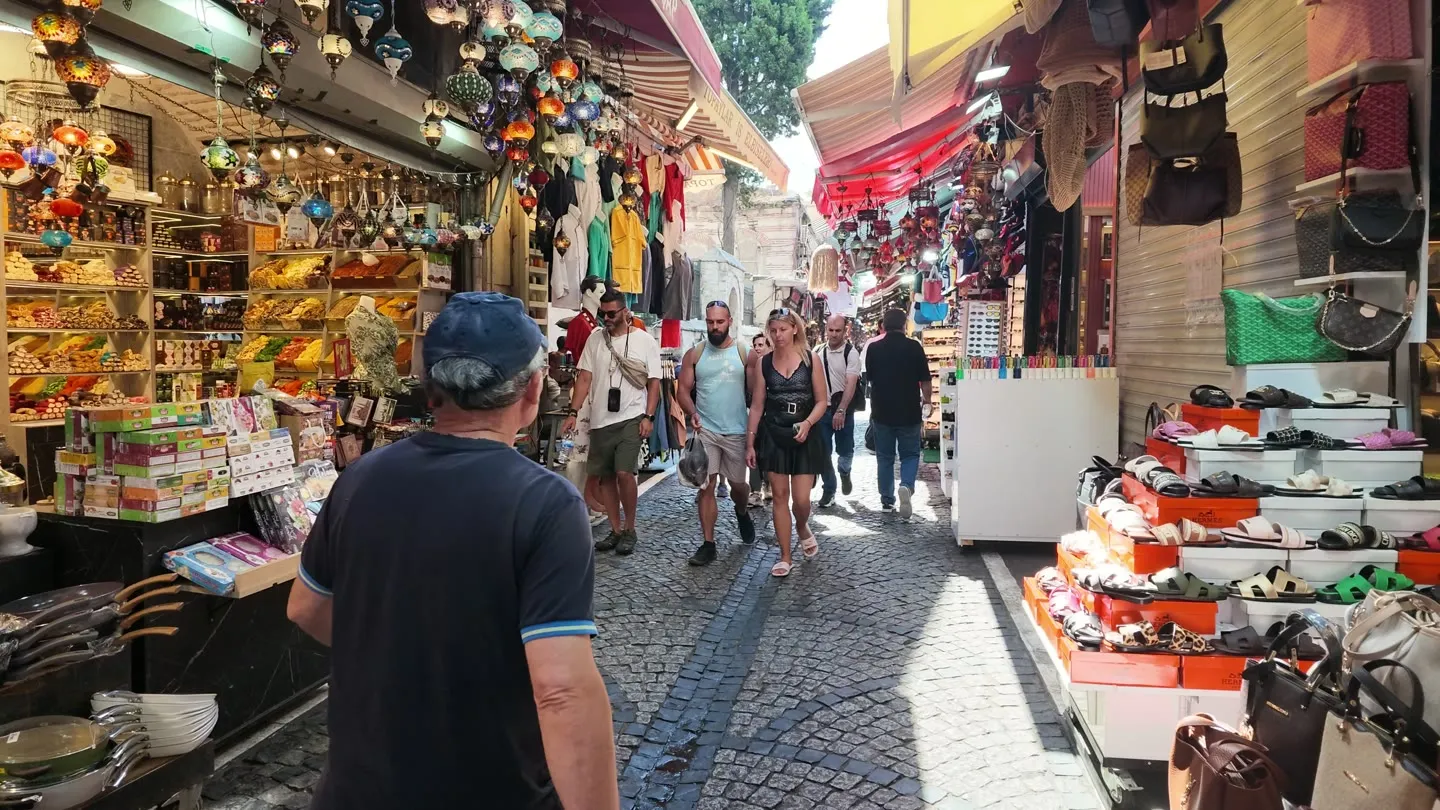 A shopper walks a narrow Istanbul market lane lined with food stalls and shopfronts