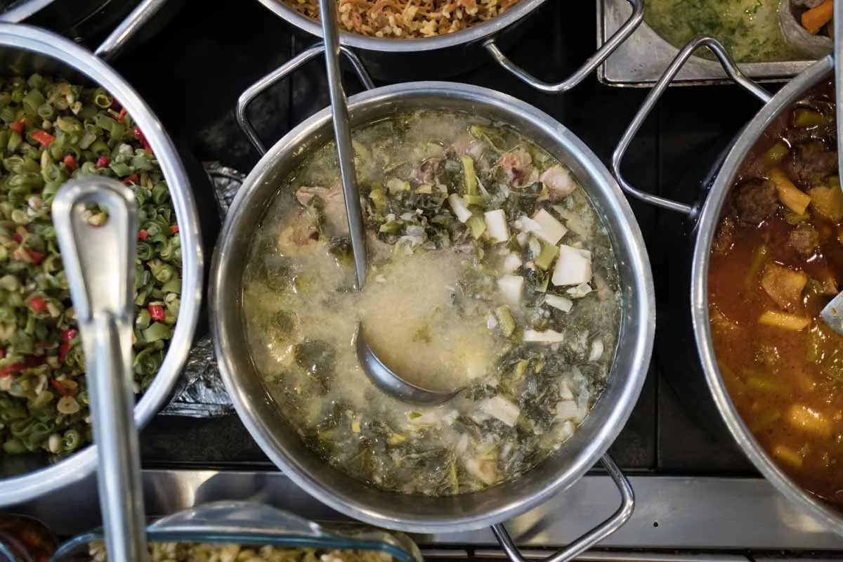 Steam-table pots of green stew, green beans, and tomato meatball stew at a Turkish eatery