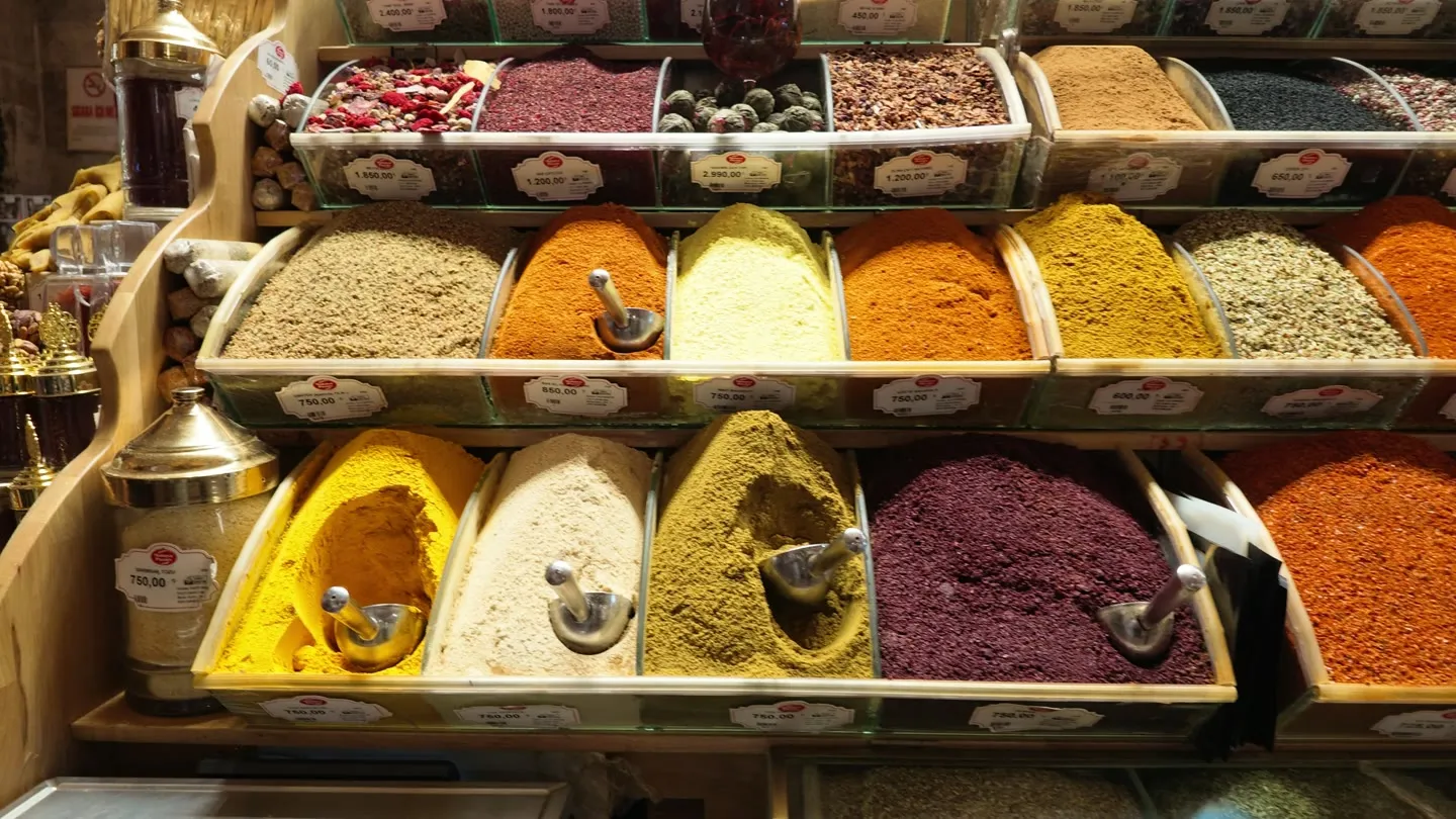 tiered wooden bins of brightly colored ground spices with scoops and price cards at an Istanbul spice shop