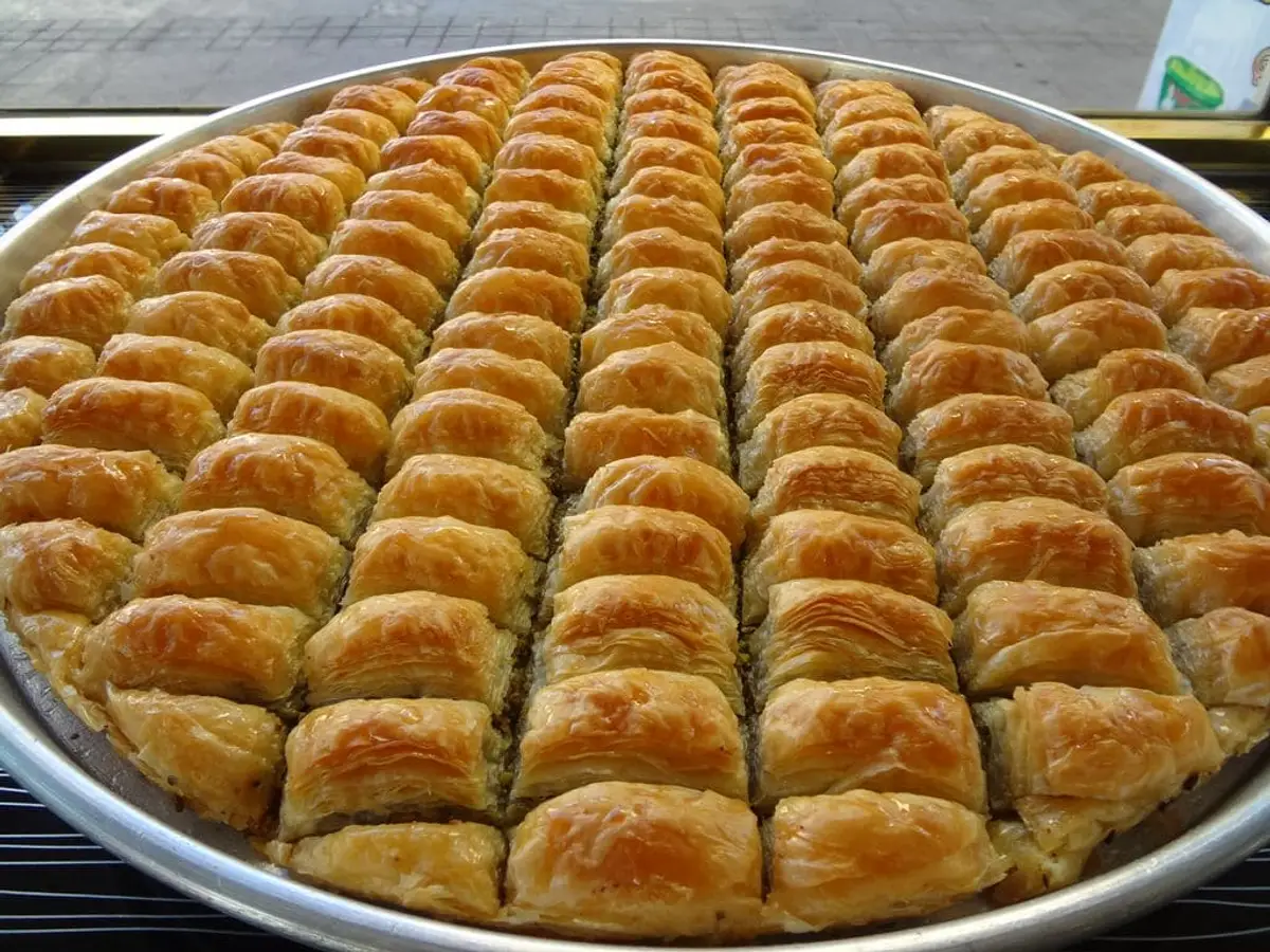 Large round tray of fresh golden crispy walnut baklava, shiny from sugar syrup