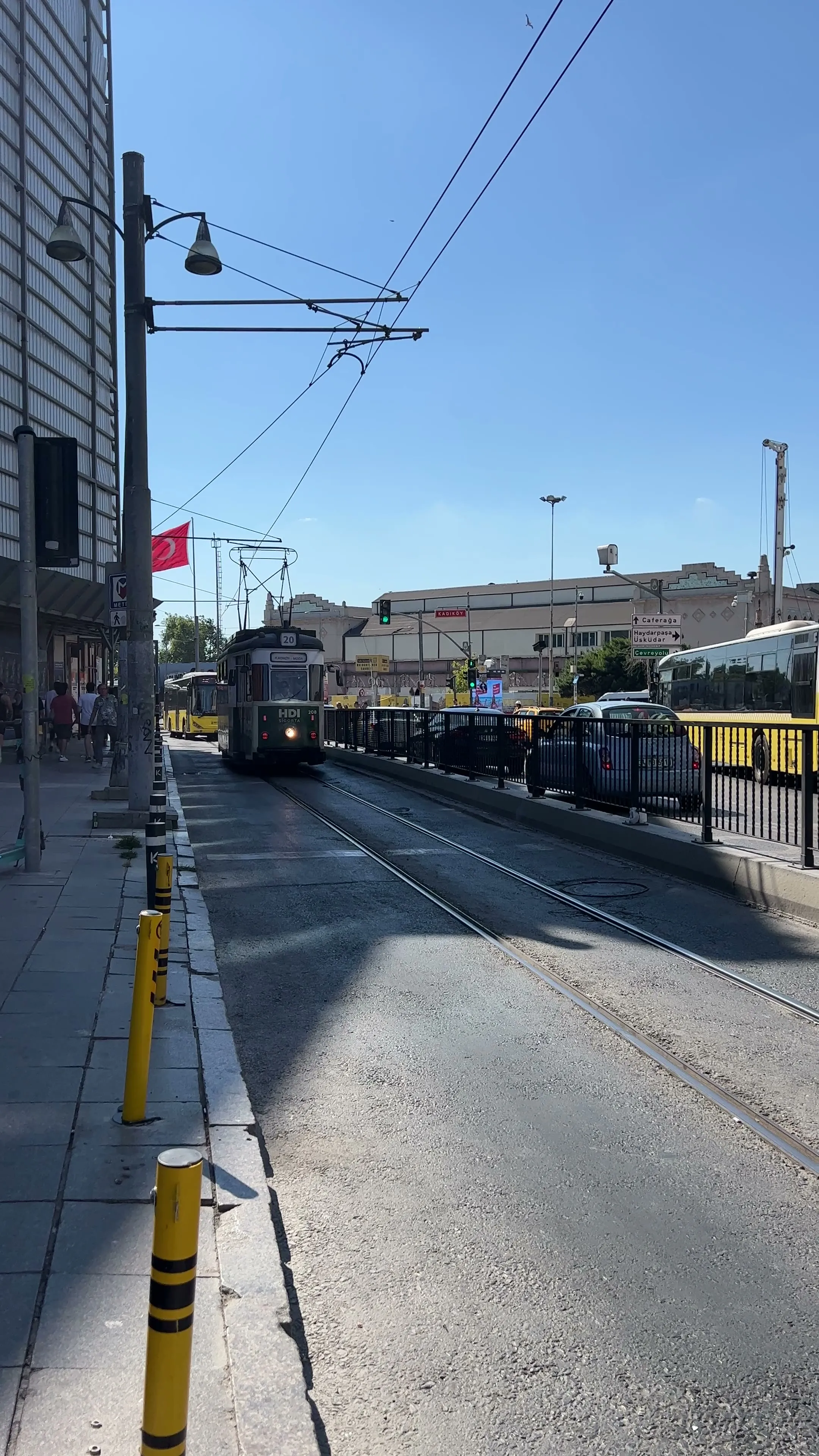 A heritage tram runs beside traffic and pedestrians near Kadıköy's waterfront