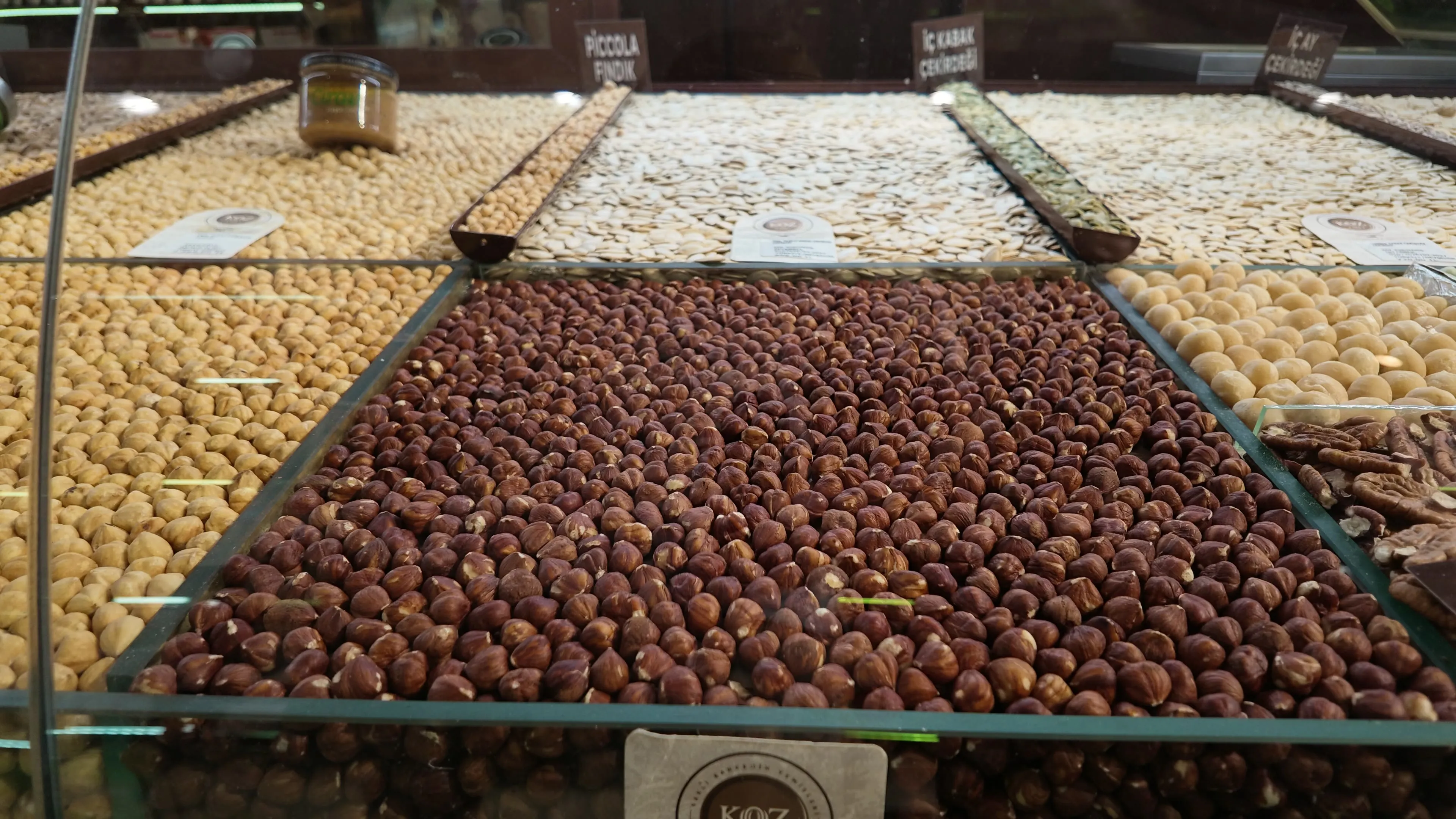 Bins of hazelnuts and pumpkin seeds behind the glass of a market counter