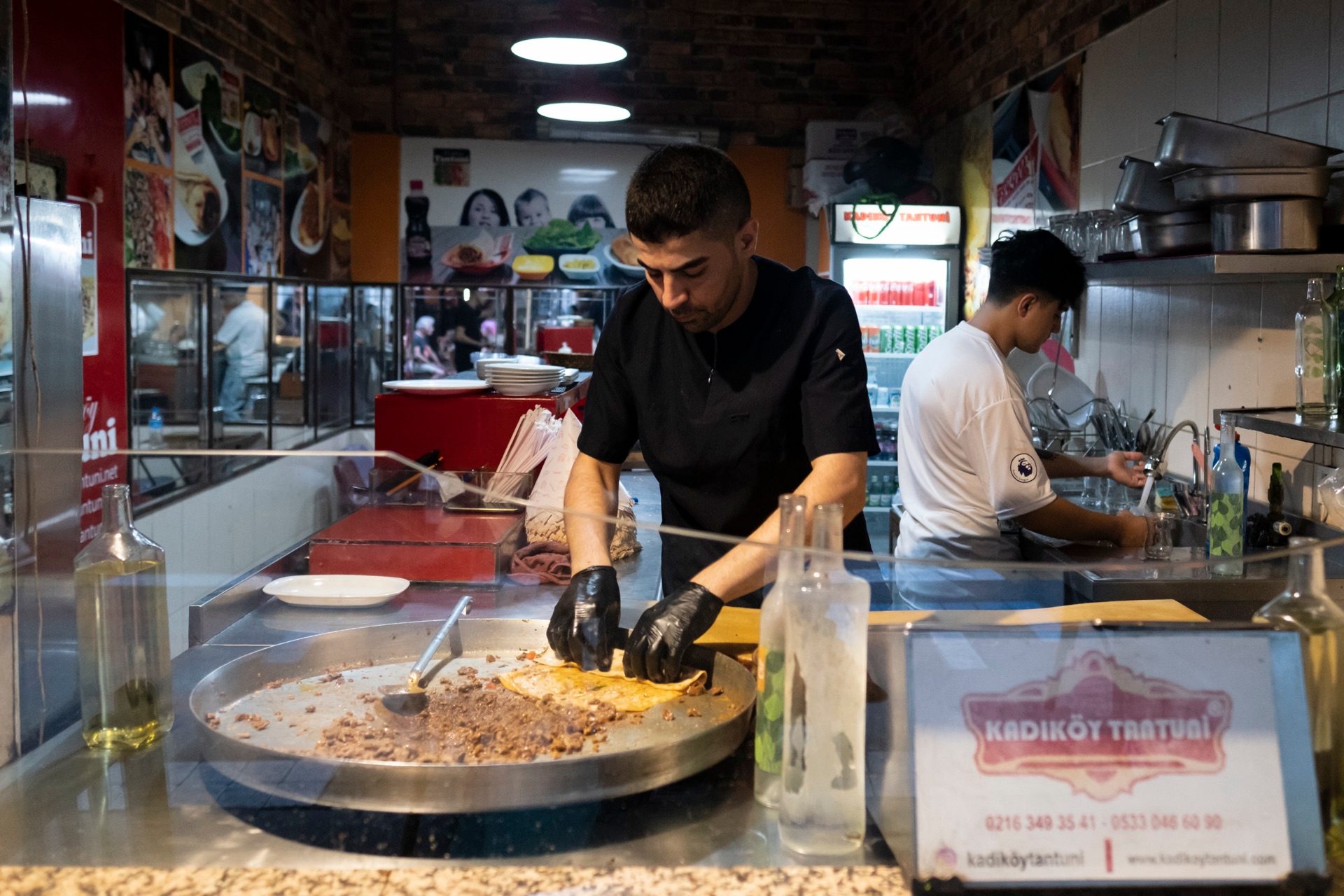 Cook griddling chopped meat at a Kadıköy street-food counter in Istanbul
