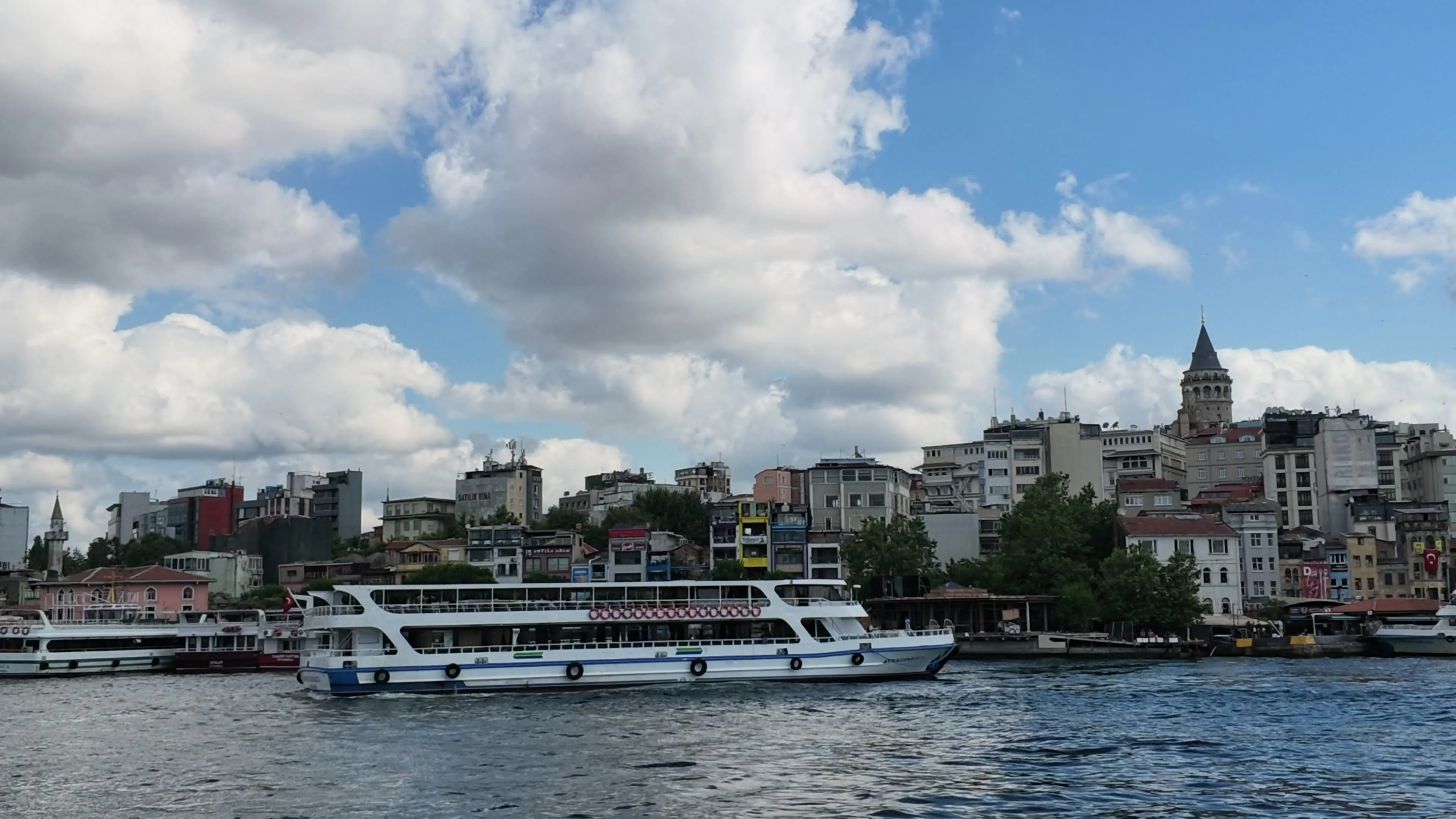A passenger ferry passes Karaköy's waterfront below Galata Tower