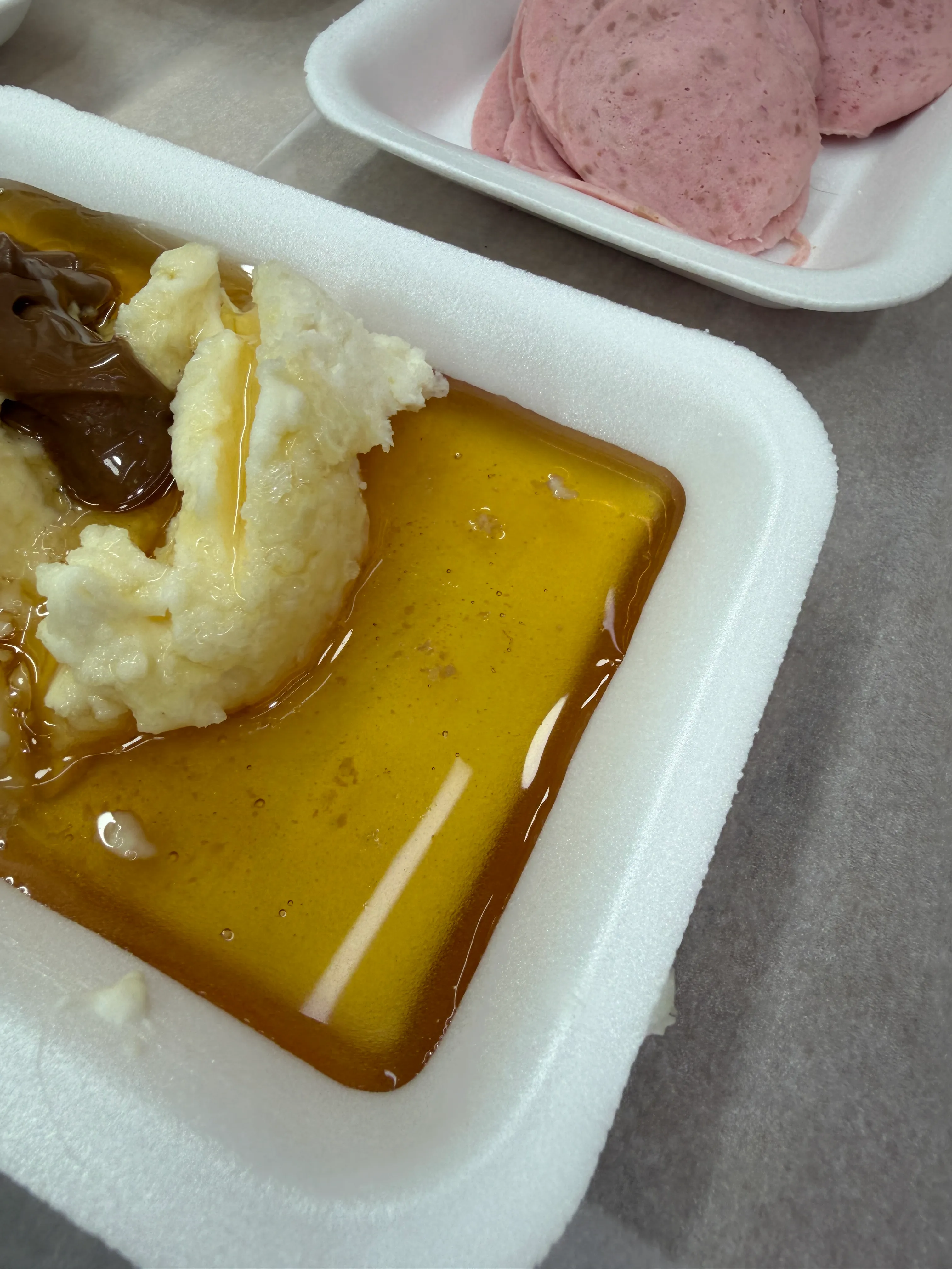 White kaymak sits in honey beside a dark spread in a rectangular serving dish