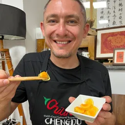 Korhan Karakoyun smiling with a bite of century egg on chopsticks in Chengdu