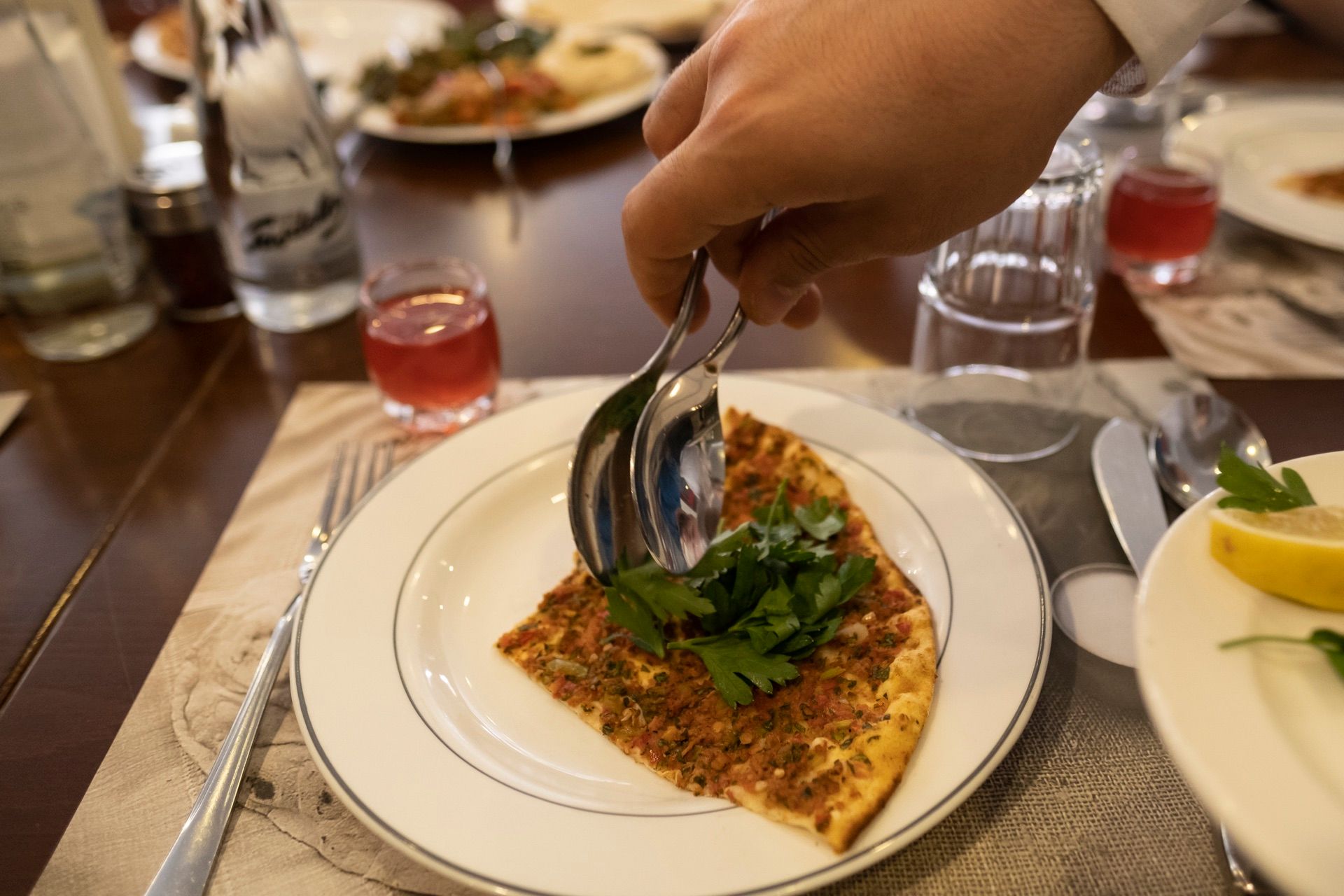 A slice of lahmacun with a fresh parsley sprig at a set table in Istanbul