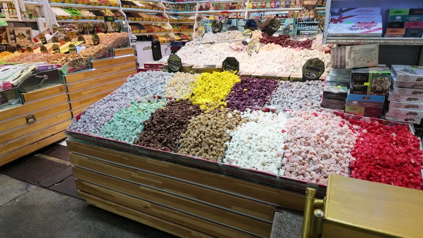 a large wooden bin of lokum divided into blocks of rose, pistachio, coconut and fruit varieties