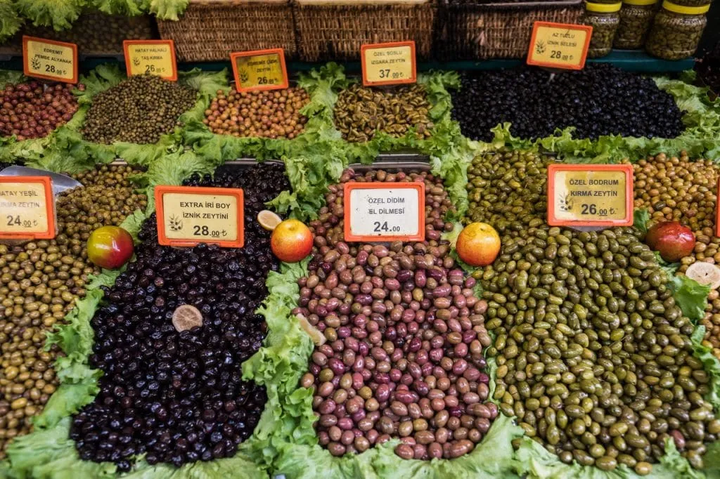 10 varieties of green and black Turkish olives in rectangular tubs on display, Istanbul food tour