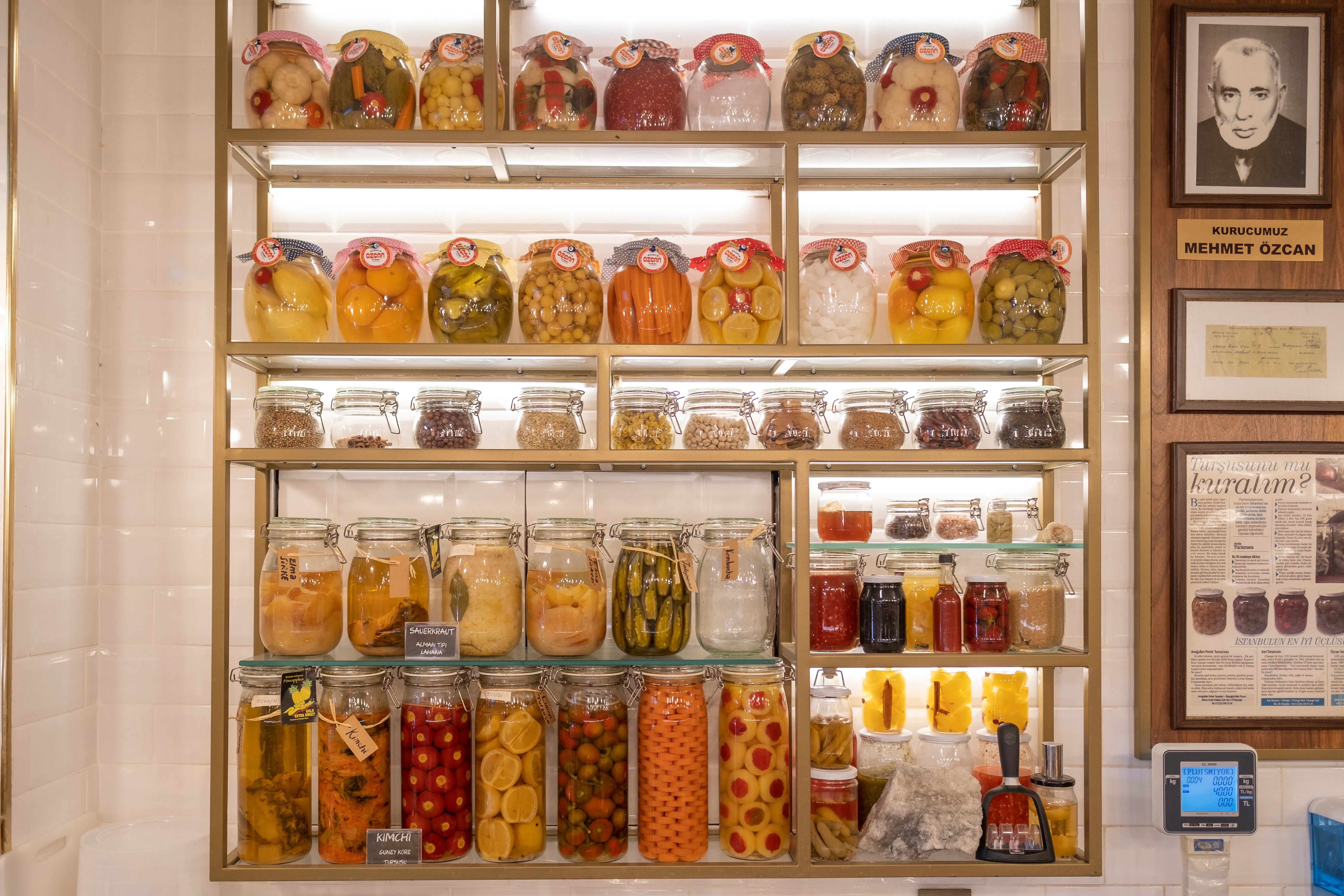 Shelves of colorful pickled vegetables in jars labeled Özcan Turşu