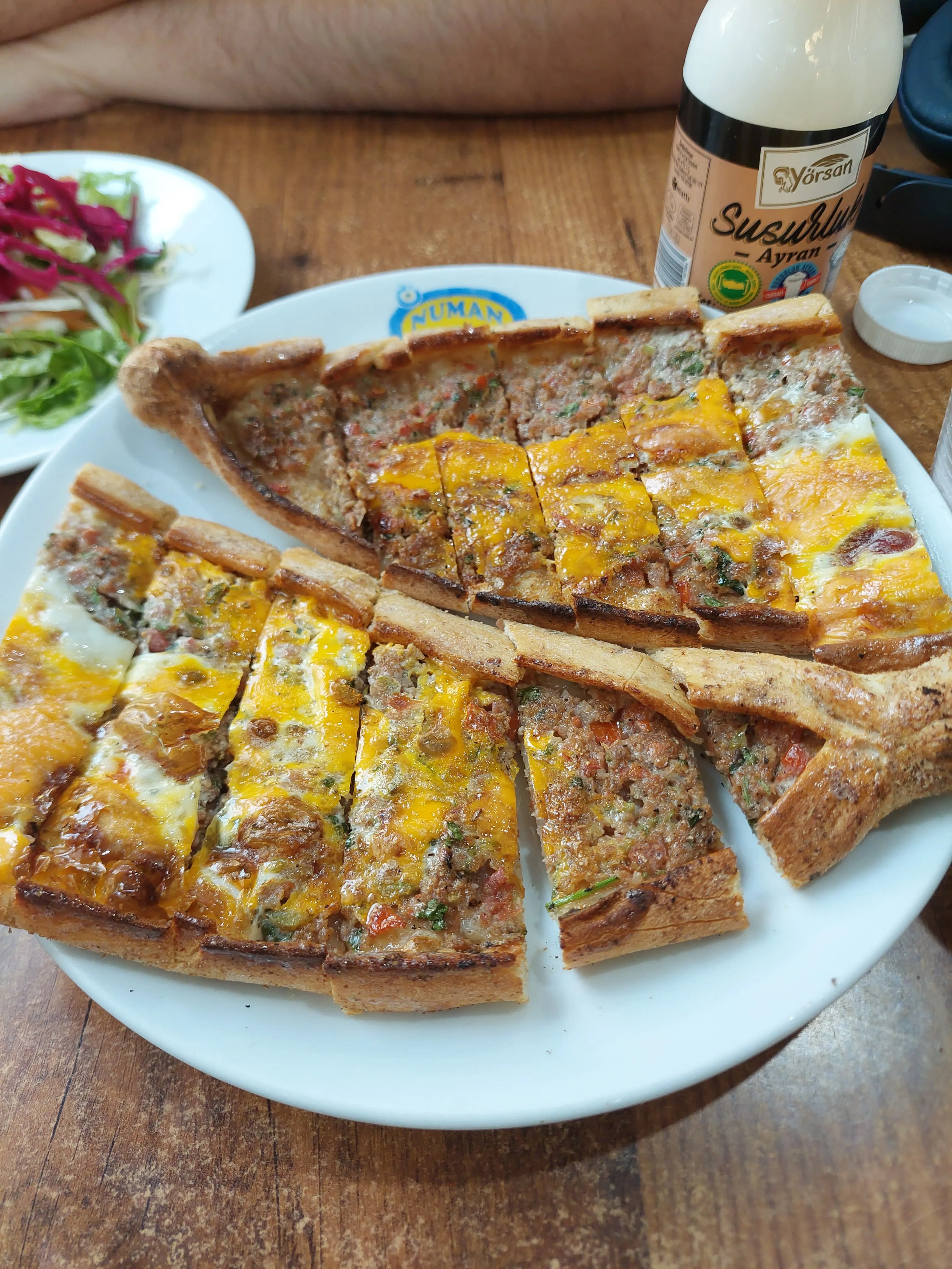 Sliced pide topped with meat and egg on a white plate