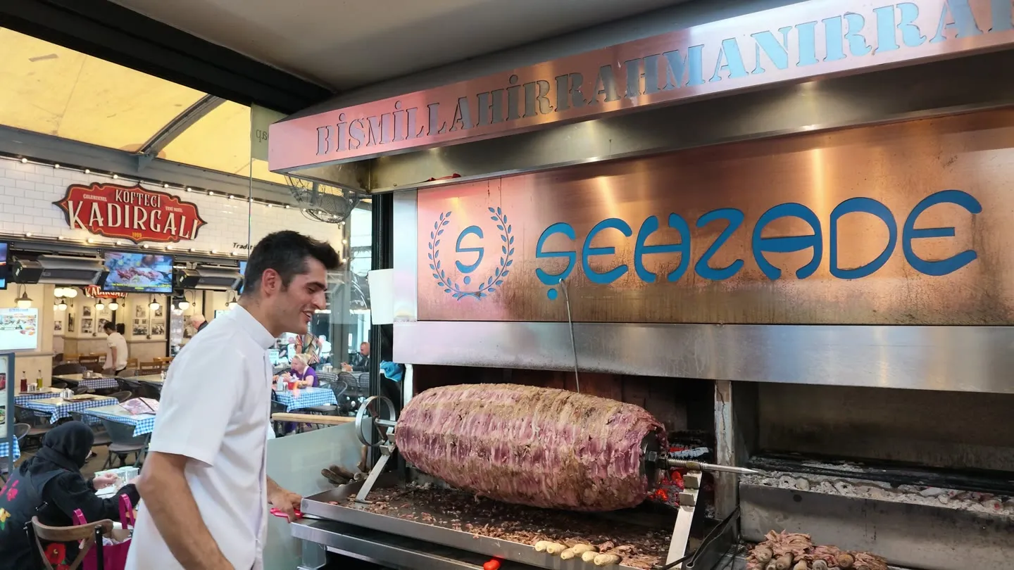 the Şehzade Cağ Kebap counter, with lamb roasting horizontally on the spit beside glowing coals