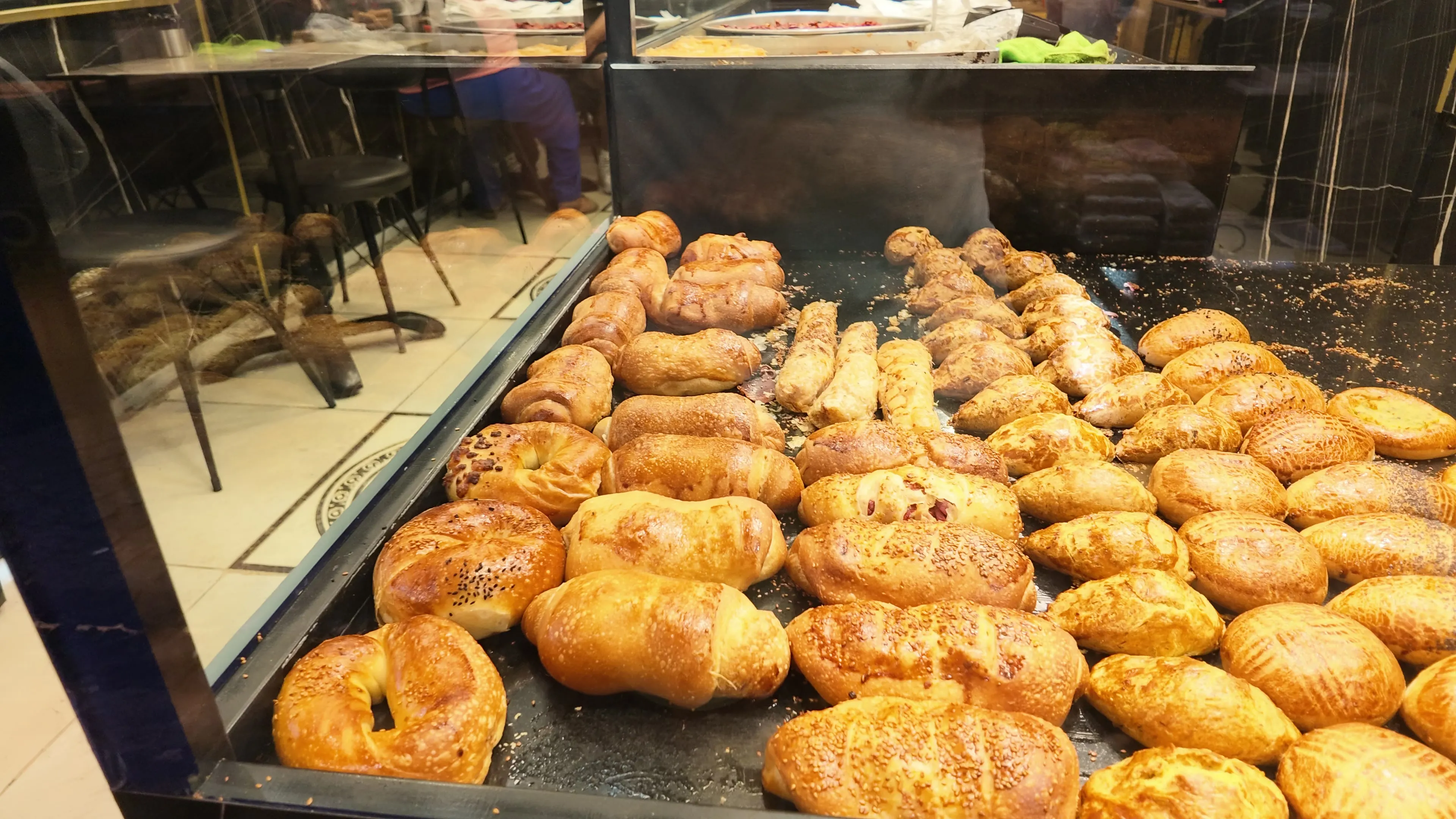 Sesame-topped bread rolls and other baked goods fill a bakery display