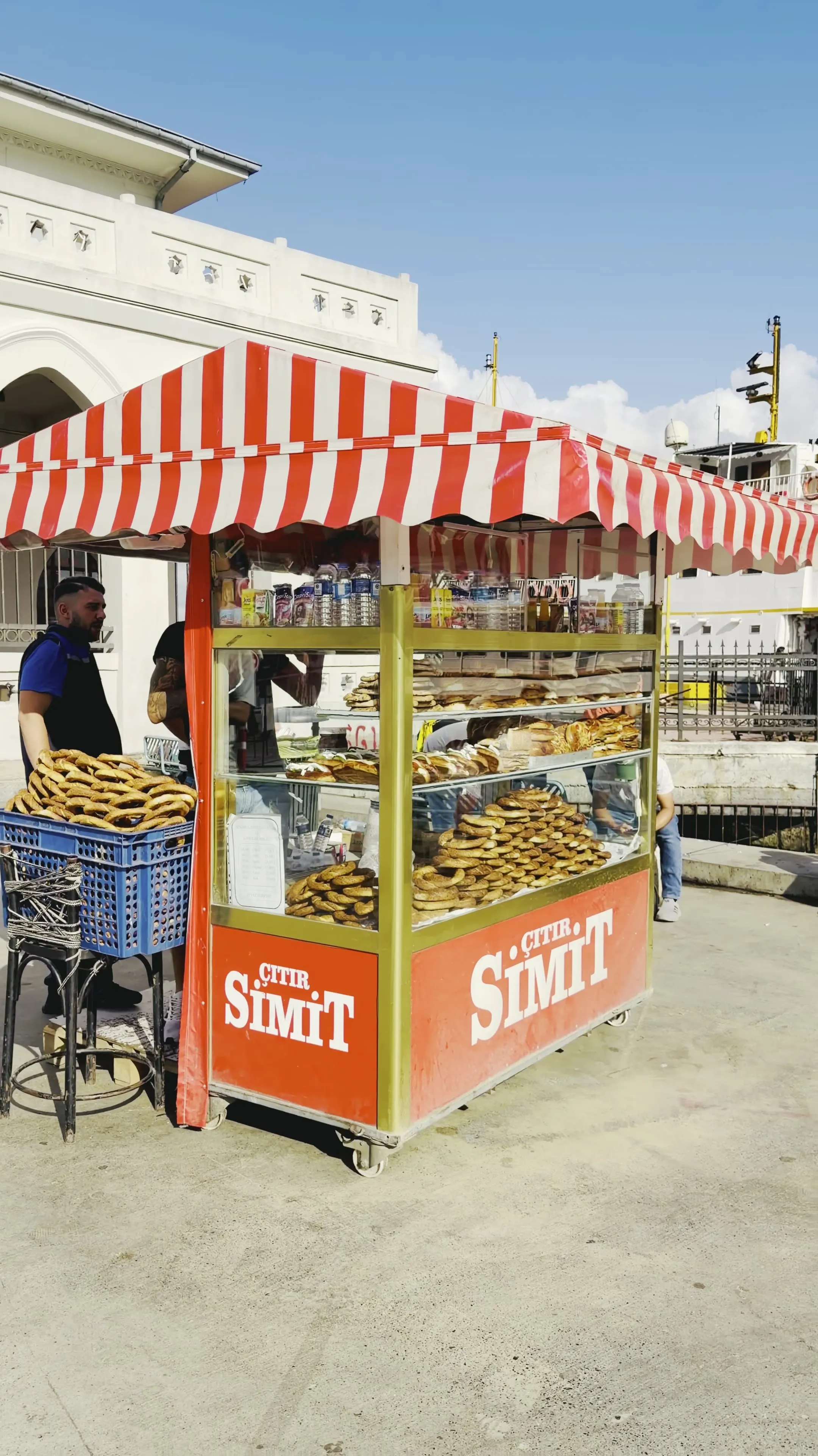 Sesame-coated simit fills a red-and-white street cart beside the waterfront