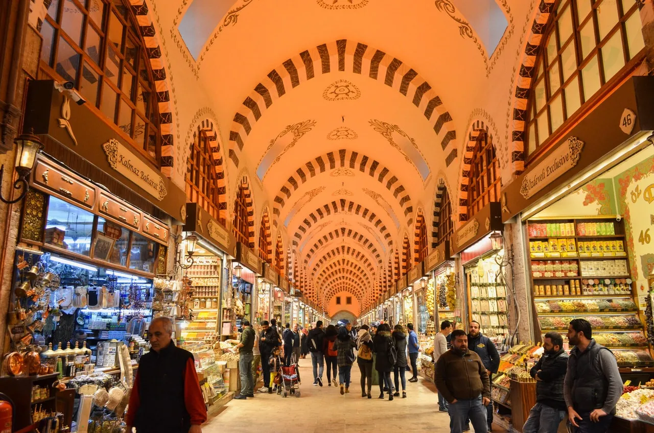 Lane inside istanbul spice bazaar, people walking past shops lining either side and traditional arched ceiling