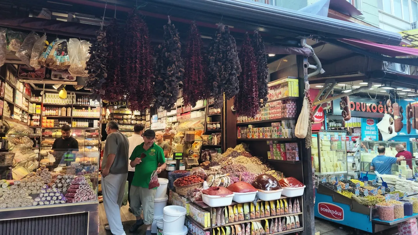 strings of dried red peppers hanging across a Tahtakale spice shopfront above open bins of ground spice