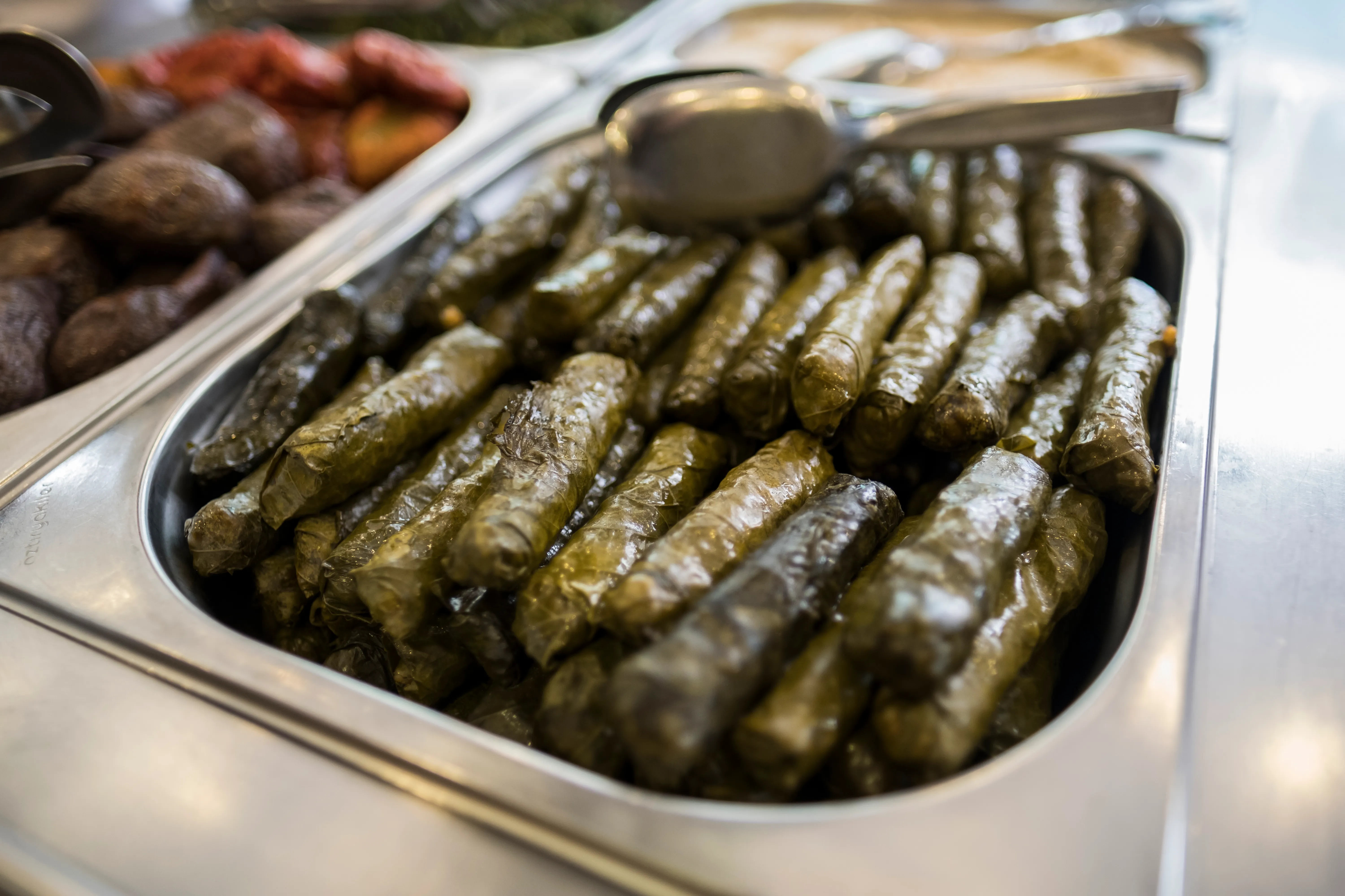 Rows of stuffed grape leaves in a stainless-steel serving tray