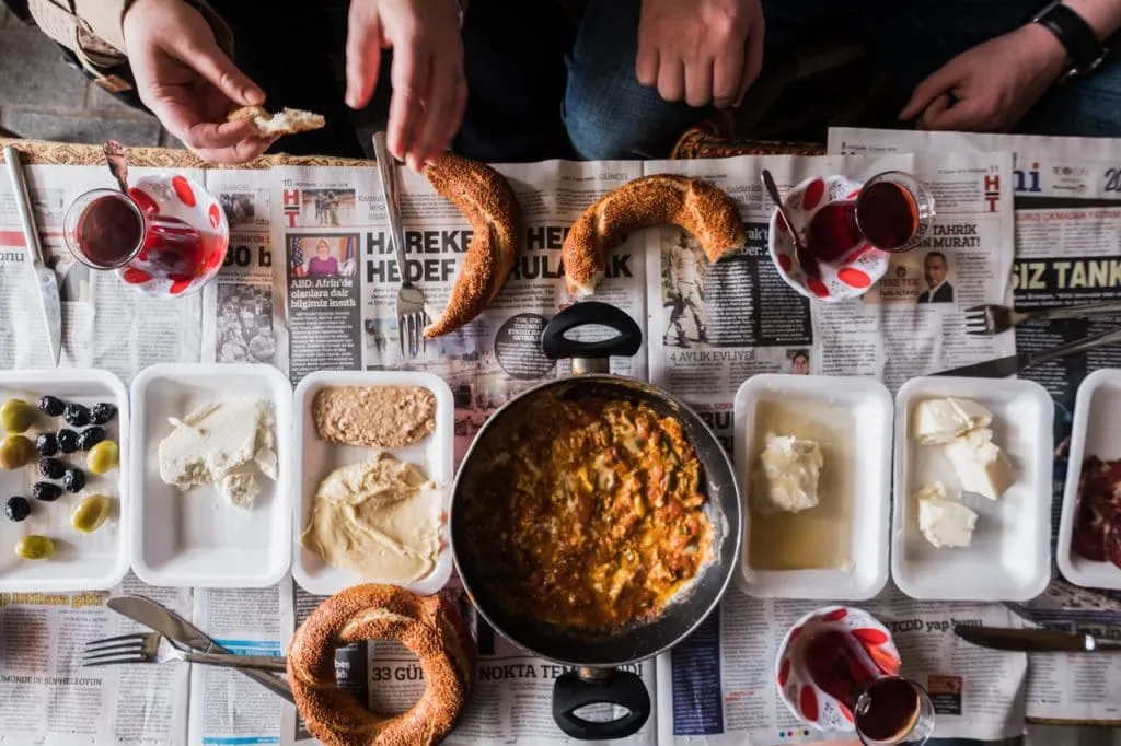 Turkish market breakfast of menemen cheese kaymak simit tea on newspaper flavors of old city tour
