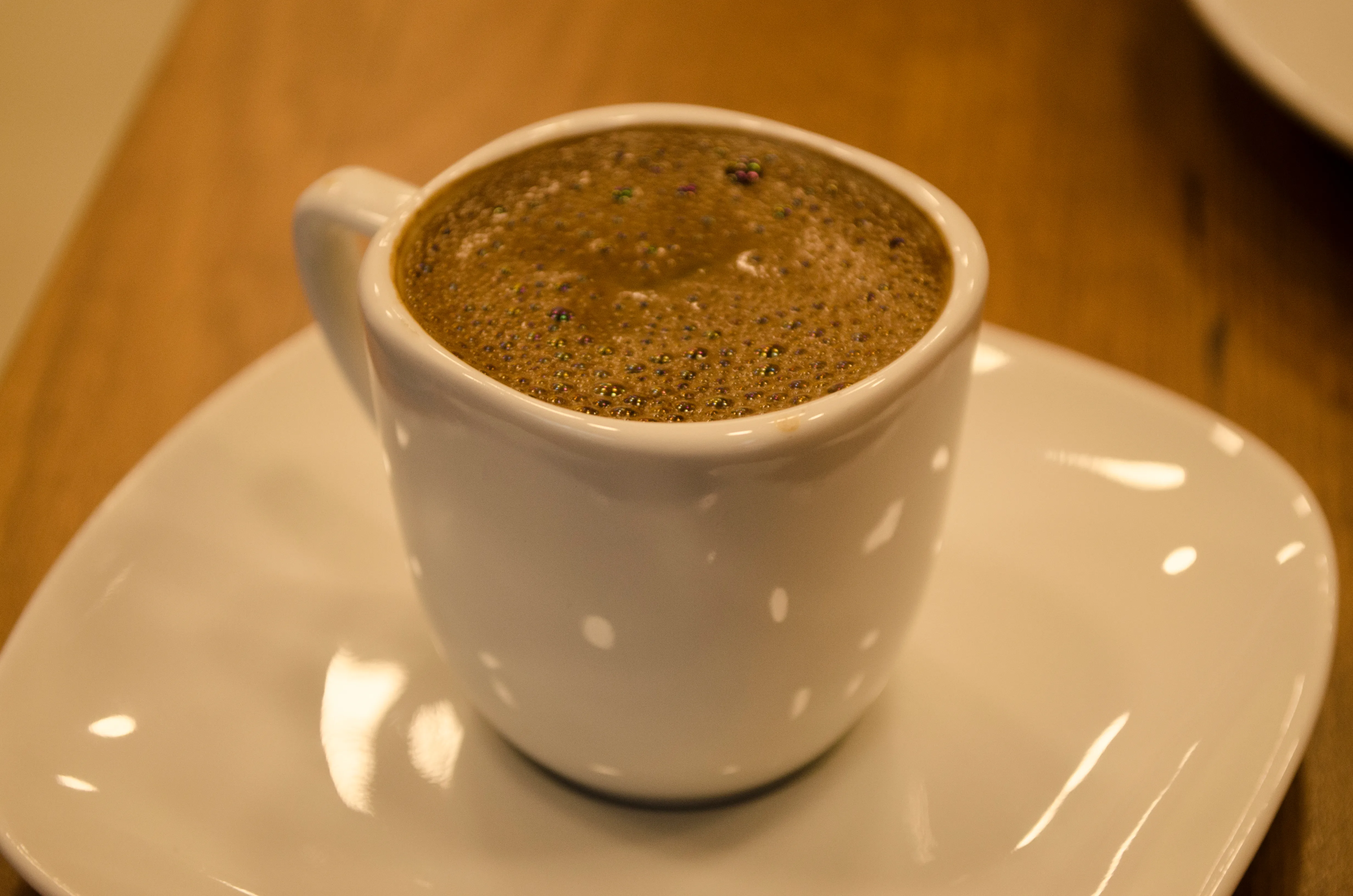 A small white cup of Turkish coffee rests on its saucer