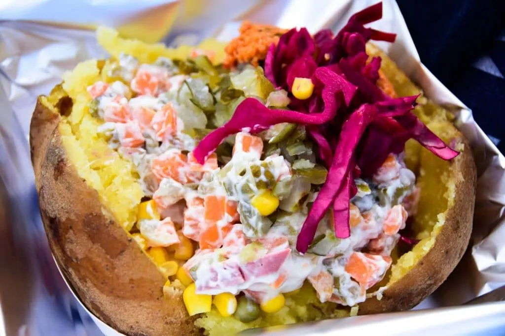 kumpir potato is filled with toppings such as russian salad, corn, cheese, butter, pickles and red cabbage