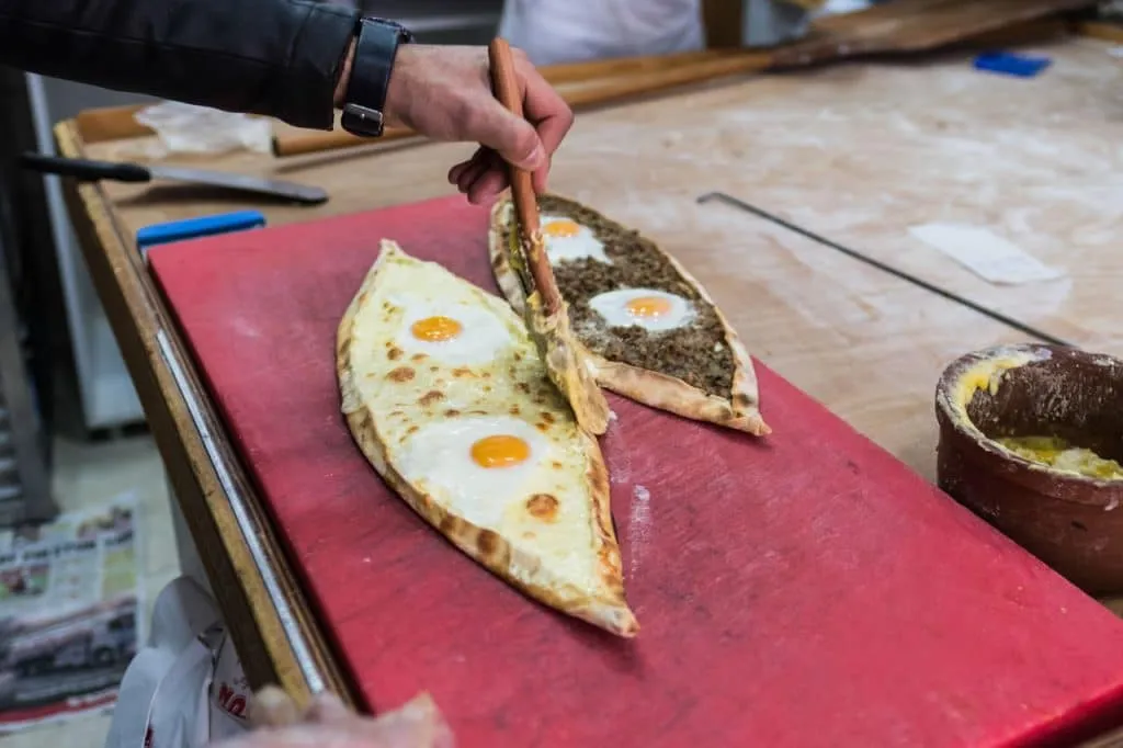 crispy cheese pide and meat pide being brushed with oil on red countertop, Istanbul culinary tour