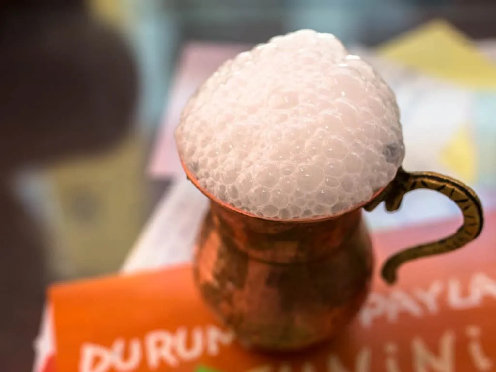 Brass cup of frothy white ayran, salty yogurt drink, one of the most popular Turkish beverages